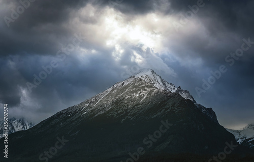 Dramatic sky with sunbeams breaking through heavy clouds over the Slavkovsky siit (peak) is the fourth highest mountain peak in the High Tatra mountains in Slovakia.