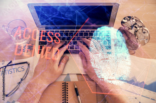 Double exposure of man's hands typing over computer keyboard and finger print hologram drawing. Top view. Personal security concept.
