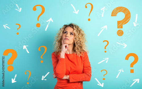 Confused and pensive expression of a girl with many questions . cyan colored background photo