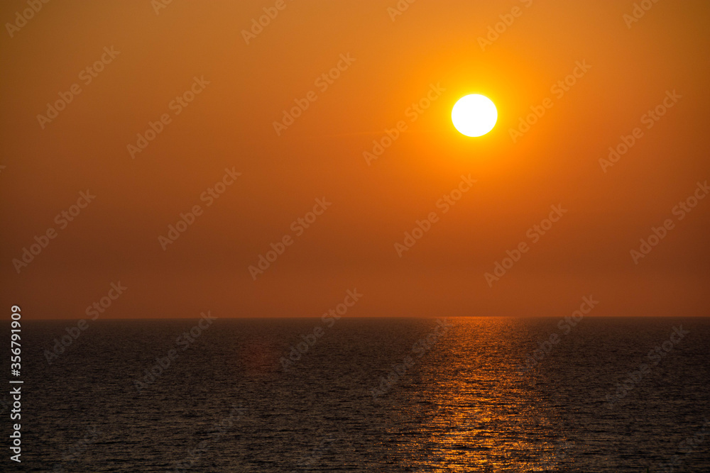 水平線に沈んでいく夕陽と輝く海