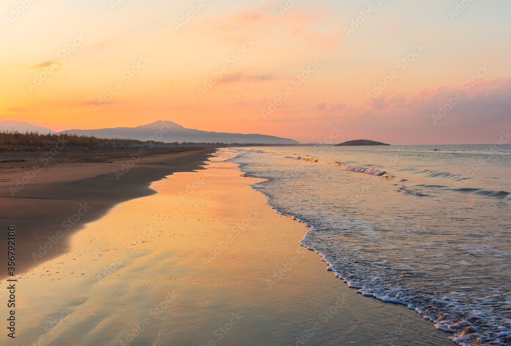 Picturesque Mediterranean seascape in Turkey. Amazing sunrise on Patara beach, Mugla Province. 
Morning orange clouds reflected in calm water.