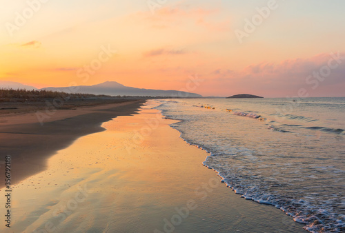Picturesque Mediterranean seascape in Turkey. Amazing sunrise on Patara beach  Mugla Province.  Morning orange clouds reflected in calm water.