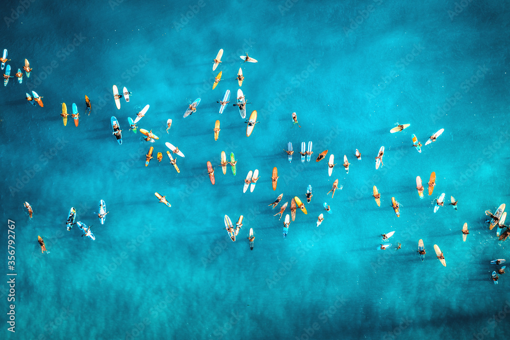 Aerial photo of big group of surfers paddle out together to support "black lives matter" at Hawaii. Colored surfboards in blue ocean top view.  - obrazy, fototapety, plakaty 