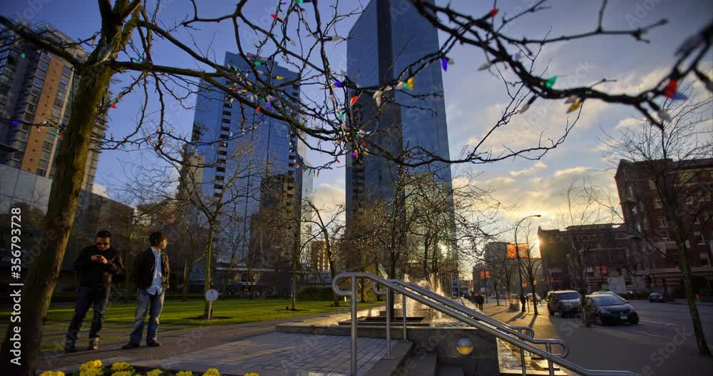Rack focus time lapse shot of string lights on branches by street against buildings in city - Vancouver, Canada