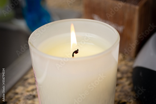 A closeup view of a lit candle on the counter.