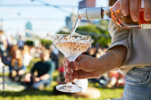 Pouring a sparkling wine in the sun at an outdoor festival.