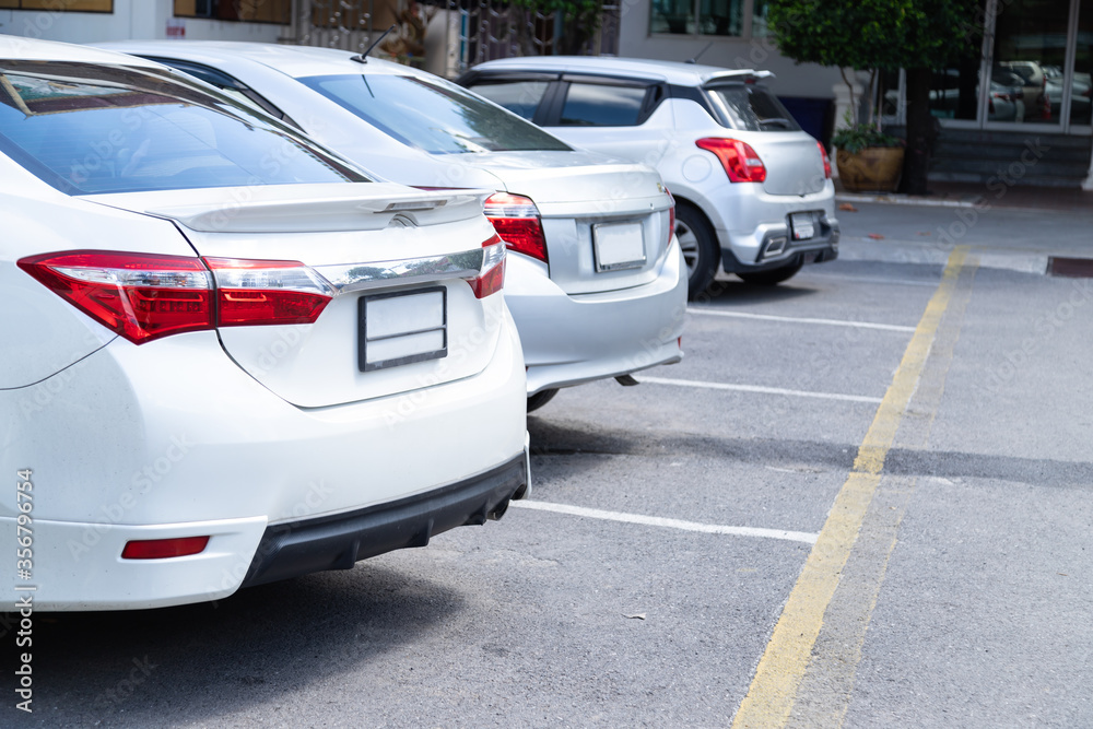 Fototapeta premium White and silver car parking in car park lot on daytime.