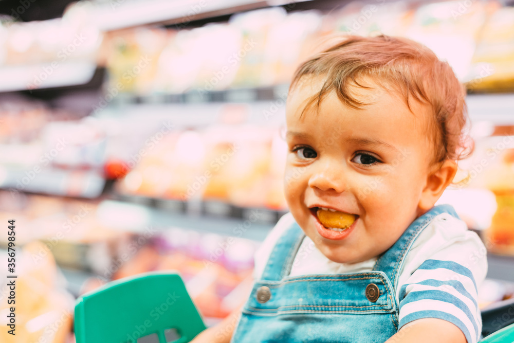 close-up of 18-month-old child in supermarket with unfocused background and eating bread close-up of 18-month-old child in supermarket with unfocused background and eating bread