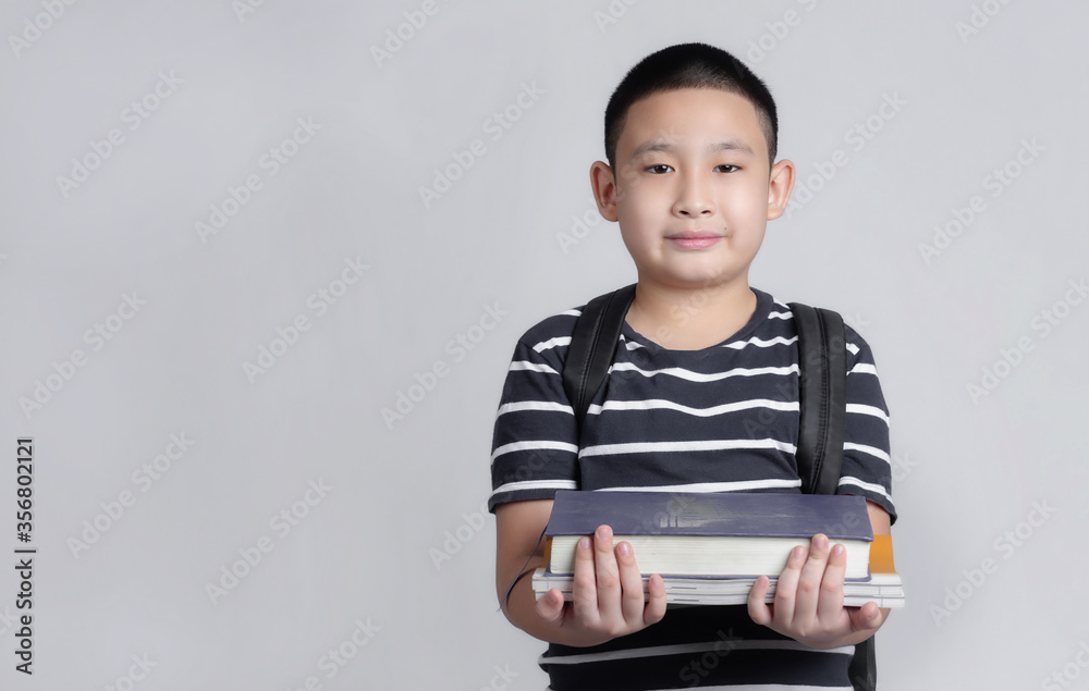 Happy boy with school bag and book in his hand. Back to school.