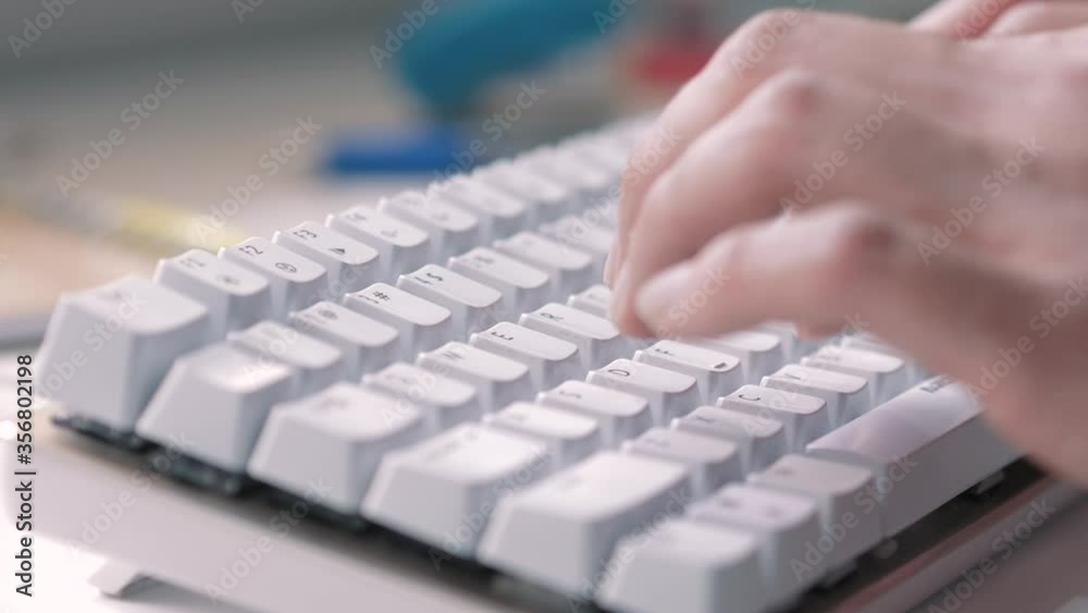 Closeup of hands typing text on a small white computer keyboard device Closeup of hands typing text on a small white computer keyboard device