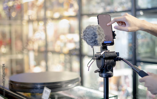 Male hand is shooting a video using gimbal and smart phone on tripod for live about the product for sell ans show the details of products