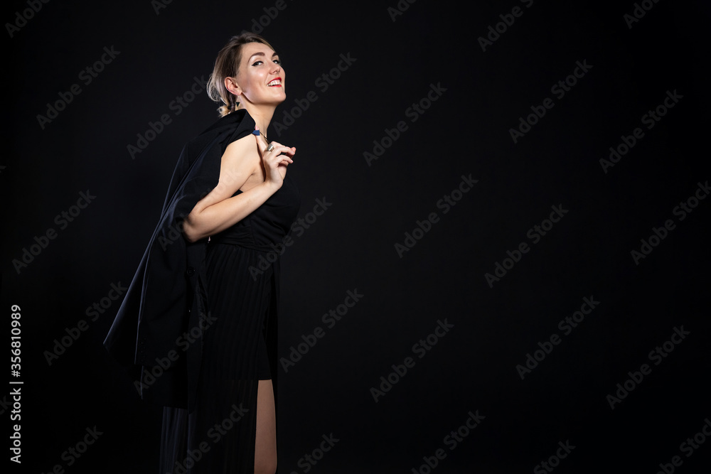 young happy girl in a black business suit on a black background, studio fashion photo with copy space young happy girl in a black business suit on a black background, studio fashion photo with copy space