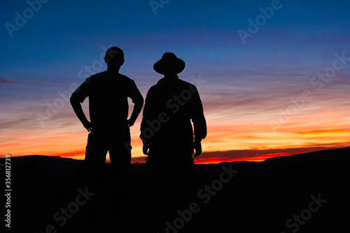 Silhouetted hikers pause to observe the sunset
