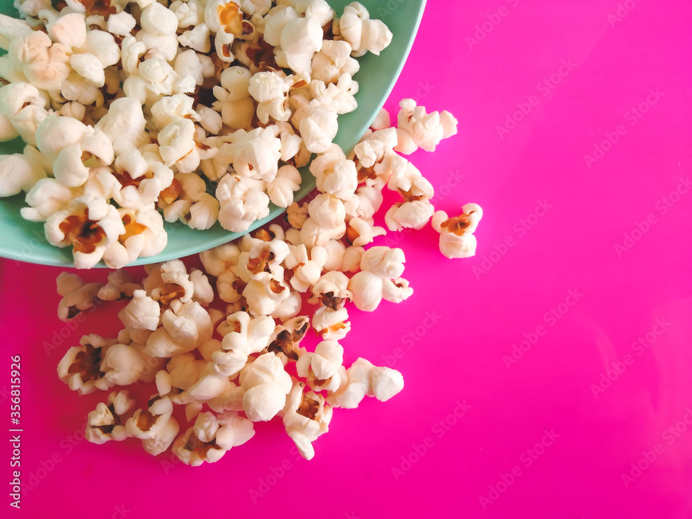popcorn composition on vibrant pink background and green bowl popcorn composition on vibrant pink background and green bowl