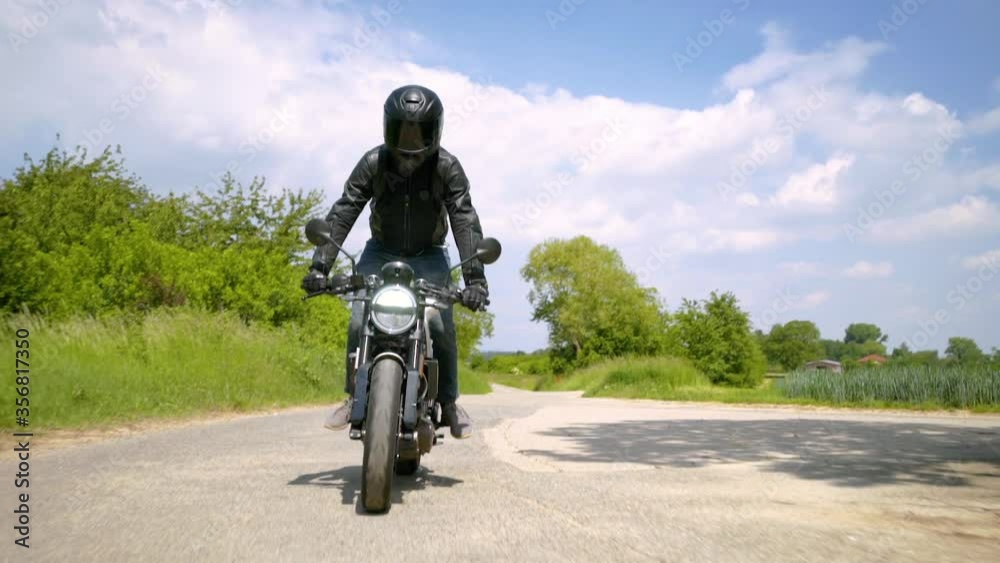 Front view of a motorcyclist goofing around on his motorcycle while riding a small path through green landscape - Slow Motion Tracking shot Front view of a motorcyclist goofing around on his motorcycle while riding a small path through green landscape - Slow Motion Tracking shot