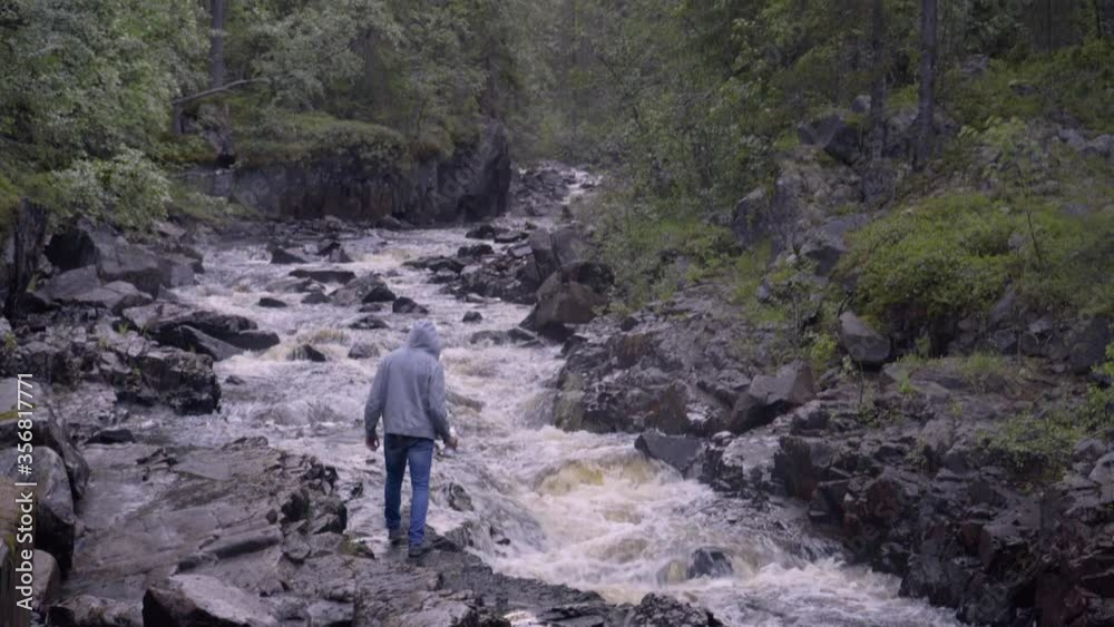 A man is drinking water from a mountain river A man is drinking water from a mountain river