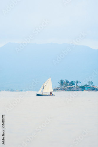 Indigenous Guna native Sailing in open sea with mountains and village in the background - Guna Yala, San Blas, Panama Central America - vertical panoramic Wide Shot