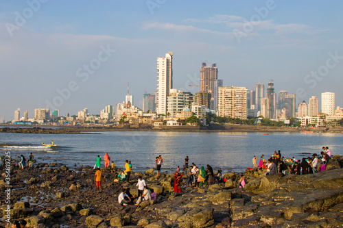 Mumbai India Nov 9th 2019: the people have fun on beach in front of Pir Haji Ali Shah Bukhari, a mosque and dargah (tomb) or the monument. The background is Haji Ali Bay and part of skyline of Mumbai. photo