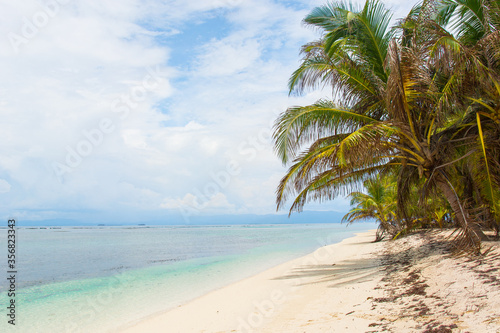 Exotic tropical beach. Clear turquoise ocean water with blue sky and white clouds. Summer vacation lifestyle tourism travel in Guna Yala San Blas Panama Central America. Horizontal Full Wide shot