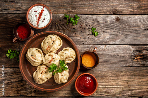 Uzbek prepared boiled Manti or manty dumplings in a traditional bowl on wooden table. banner menu recipe place for text
