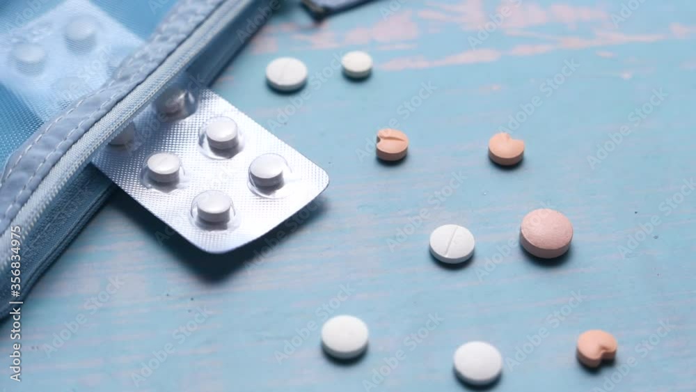Top view of white pills spilling on wooden table Top view of white pills spilling on wooden table