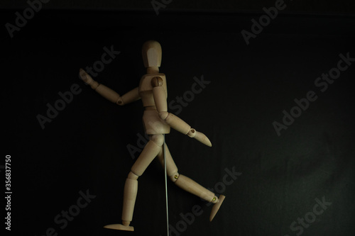 wooden mannequin running pose on black background