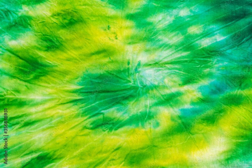 Yellow green spiral tie dye background on fabric. Flat lay. Stock Photo