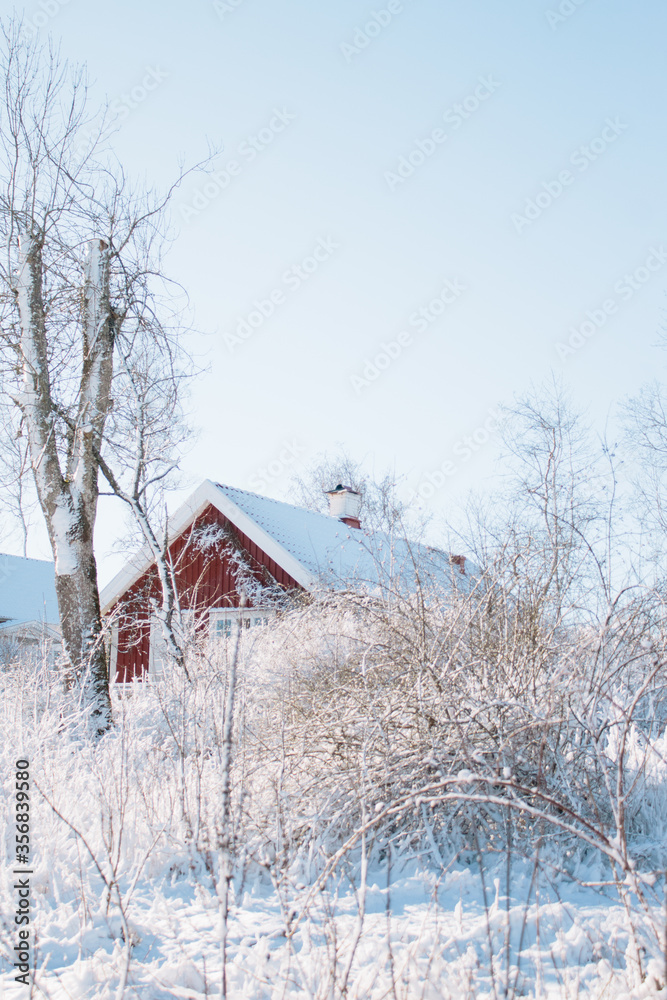 Typical Swedish winter scene, an old red farmhouse in the snow, sunshine and blue sky