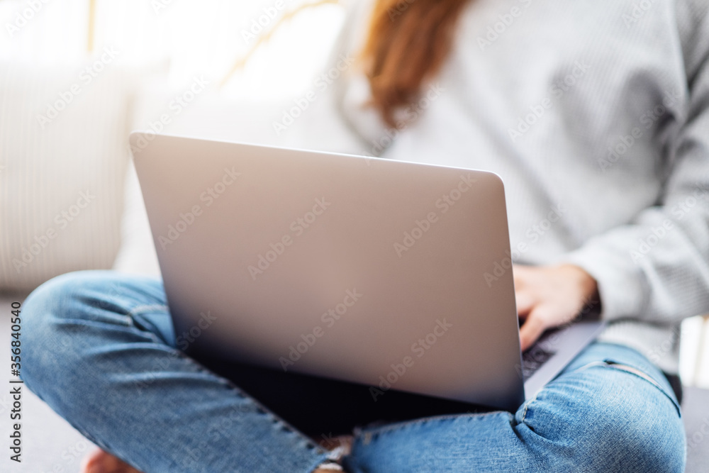 A beautiful woman using and working on laptop computer while sitting on a sofa at home A beautiful woman using and working on laptop computer while sitting on a sofa at home