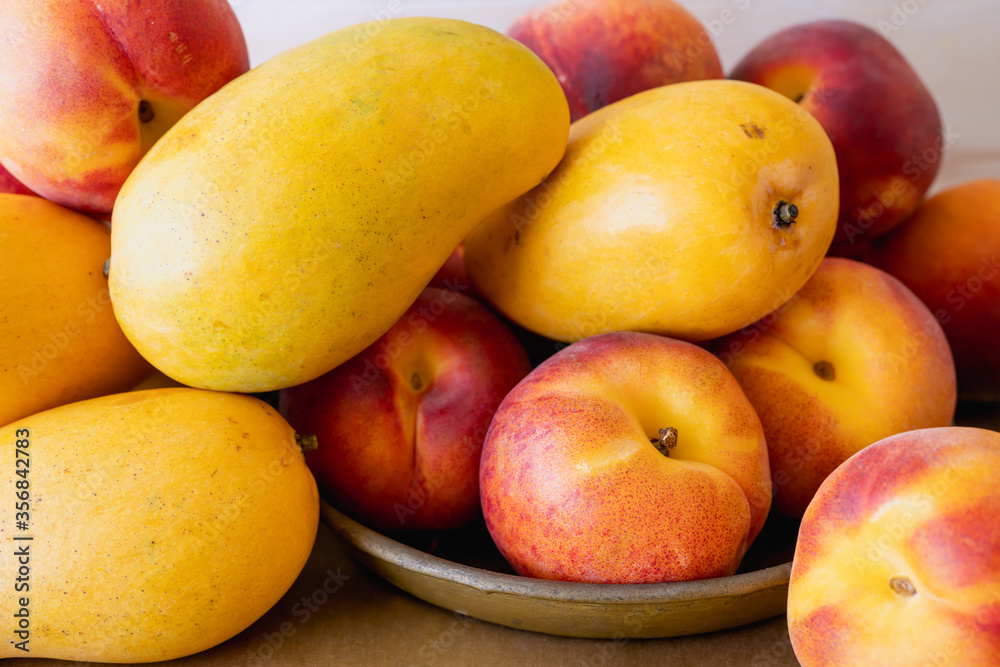 Yellow mangoes and peaches. Fresh ripe organic tropical fruits close up Yellow mangoes and peaches. Fresh ripe organic tropical fruits close up