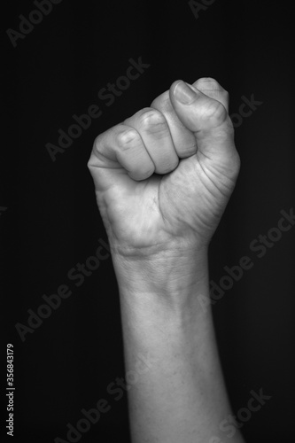 Female raised fist isolated on black background