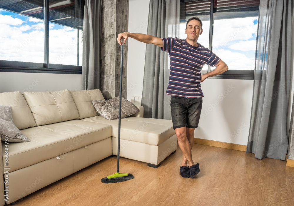 Smiling man sweeping his living room. Smiling man sweeping his living room.