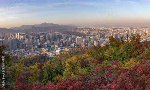 Panoramic view of the city Seoul in autumn, taken from N Seoul Tower. City skyline, skyscrapers and hills. Red and green trees in the forest surrounding the city. Aerial view. Seoul, South Korea, Asia