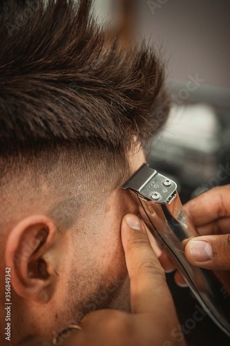 Fotka „Barbeiro cortando cabelo do seu cliente da sua barbearia no estilo  vintage, usando tesoura e navalha e máquina de cortar barbeador elétrico“  ze služby Stock | Adobe Stock
