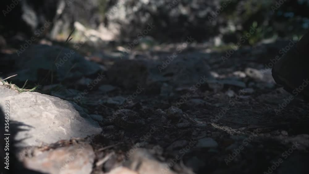 Close up feet of female hiker walking, climbing on rocky trail in hiking boots. Footsteps of hiker in nature kicking up rocks Close up feet of female hiker walking, climbing on rocky trail in hiking boots. Footsteps of hiker in nature kicking up rocks