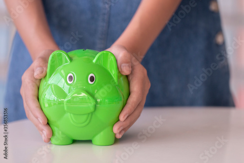 hand holding bright green piggy bank and money photo