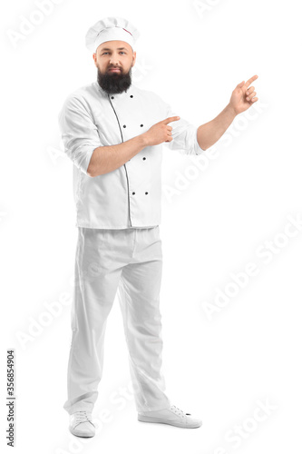 Handsome male chef pointing at something on white background