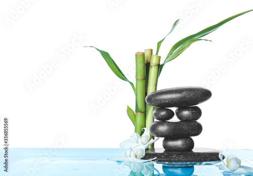 Spa stones  bamboo and flowers in water against white background
