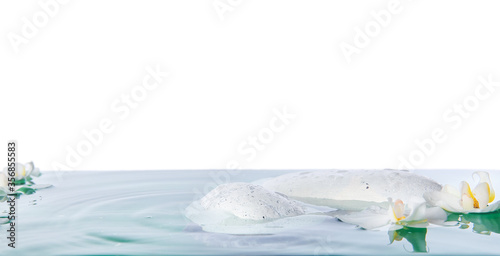 Spa stones and flowers in water against white background