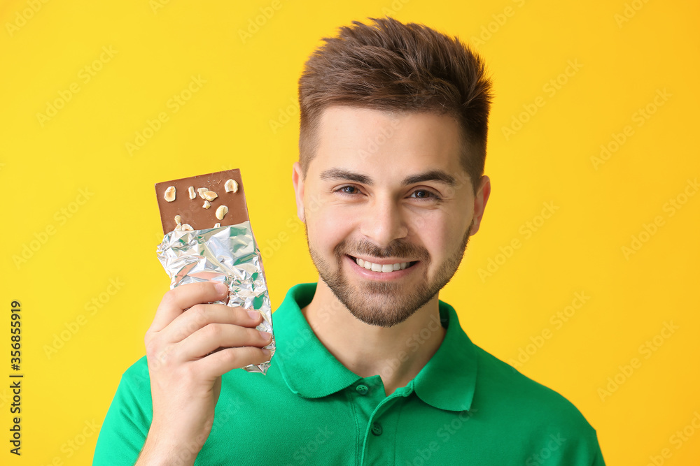 Handsome young man with tasty chocolate on color background Handsome young man with tasty chocolate on color background