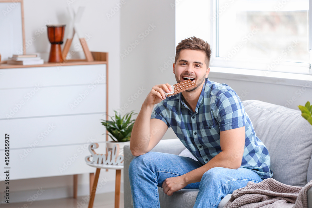 Fototapeta premium Handsome young man with tasty chocolate at home