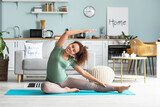Young pregnant woman practicing yoga at home