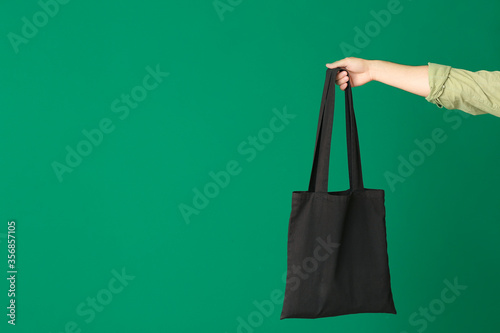 Male hand with eco bag on color background