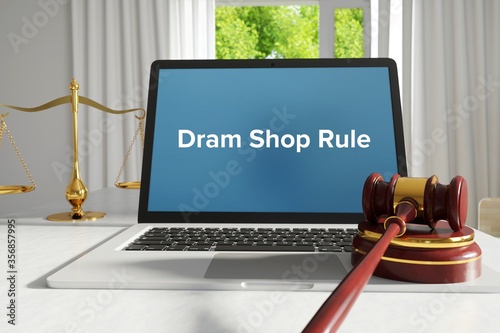 Dram Shop Rule – law, jurisdiction. A lawyer laptop in the office on desk. Text on the screen. Libra and hammer