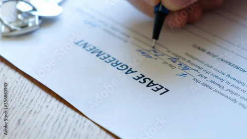 Unrecognizable man filling a rental agreement form, lease contract. Close up