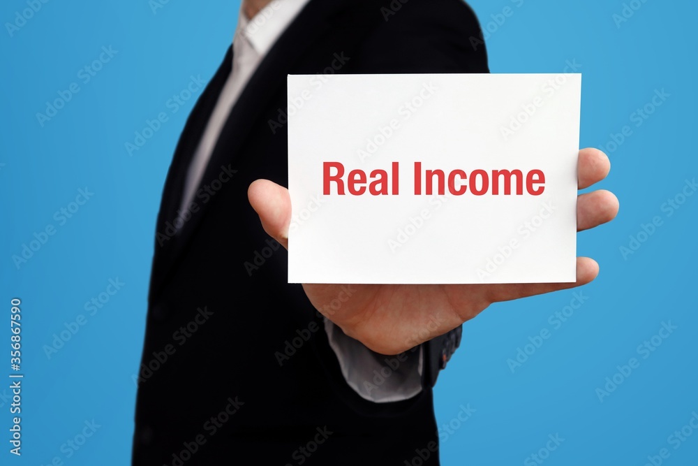 Real Income. Businessman (Man) holding a card in his hand. Text on the board presents term. Blue background. Business, Finance, Statistics, Analysis, Economy Real Income. Businessman (Man) holding a card in his hand. Text on the board presents term. Blue background. Business, Finance, Statistics, Analysis, Economy