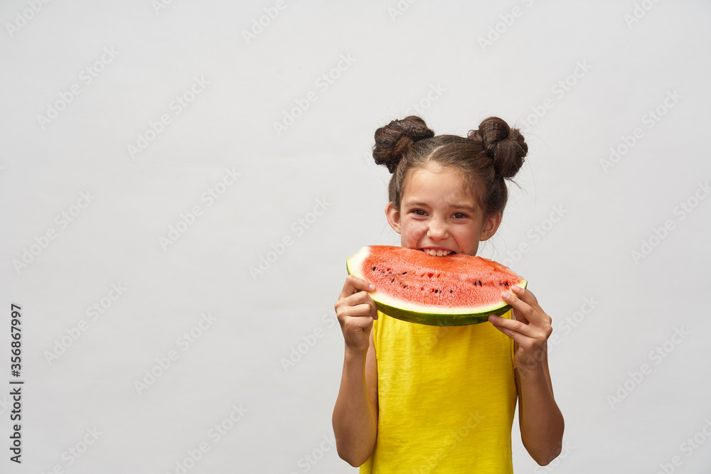 little girl in yellow t-shirt, laughing merrily and biting slice of watermelon little girl in yellow t-shirt, laughing merrily and biting slice of watermelon