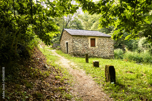 Old stone mill in forest surrounded by nature and ancient leafy trees in Sarria, Galicia