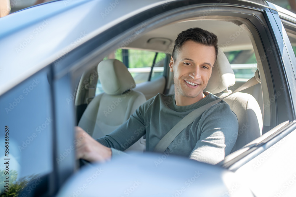 Young adult smiling man driving a car Young adult smiling man driving a car