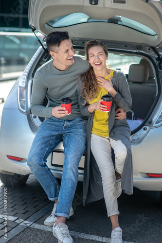 Young beautiful man and woman drinking coffee near a car © zinkevych